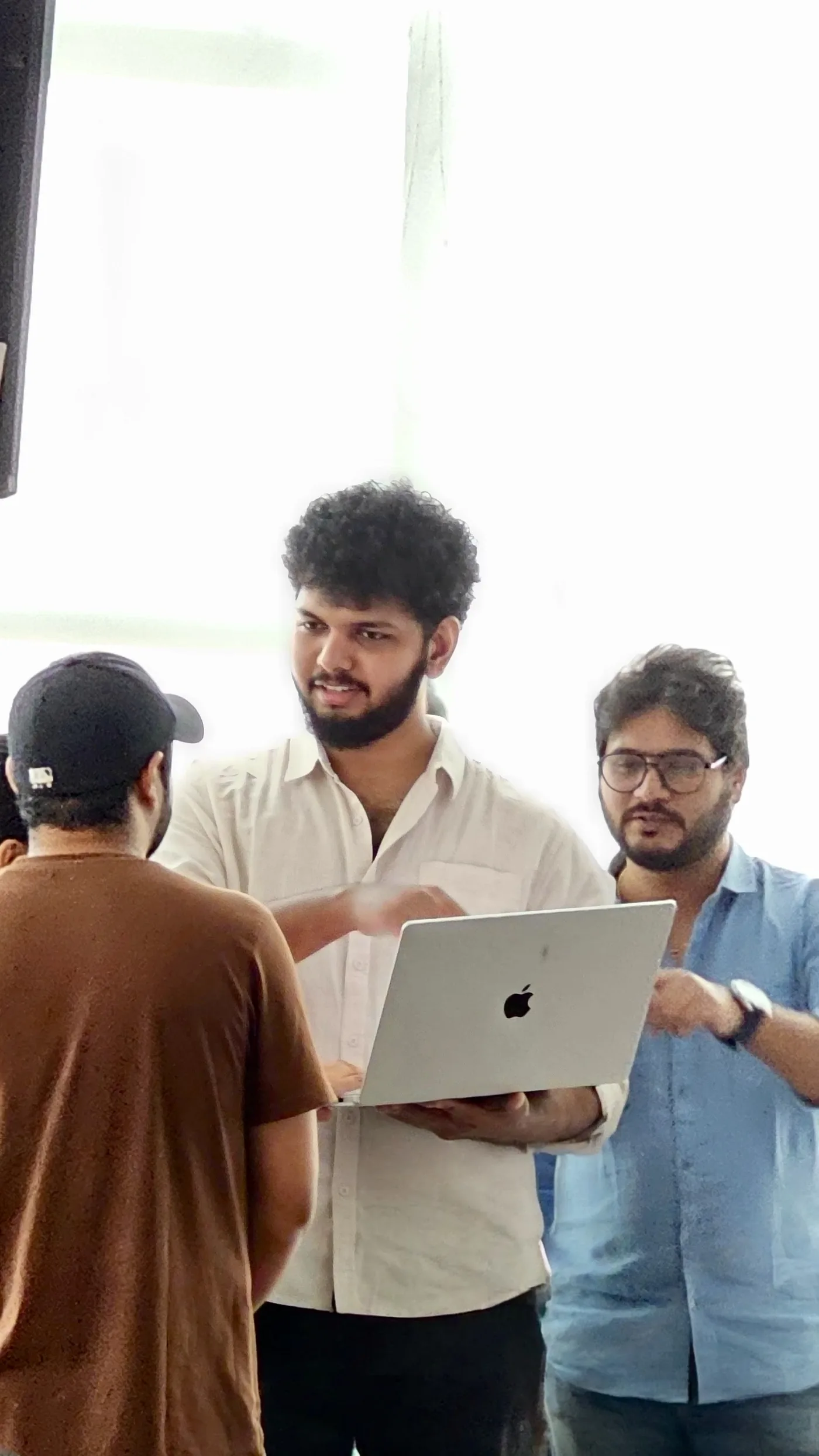 Alvin holding a laptop while discussing work with others